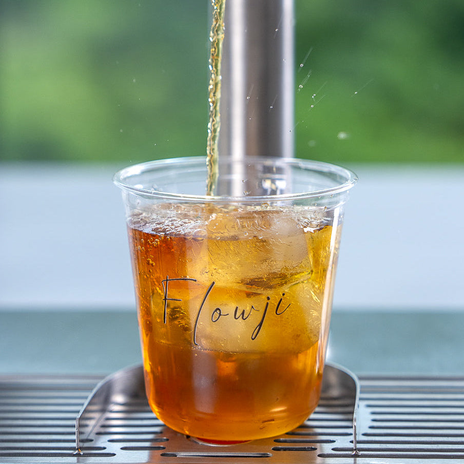 Fresh tea poured into a Flowji cup with ice, showcasing live beverage preparation at a Flowji catering cart.