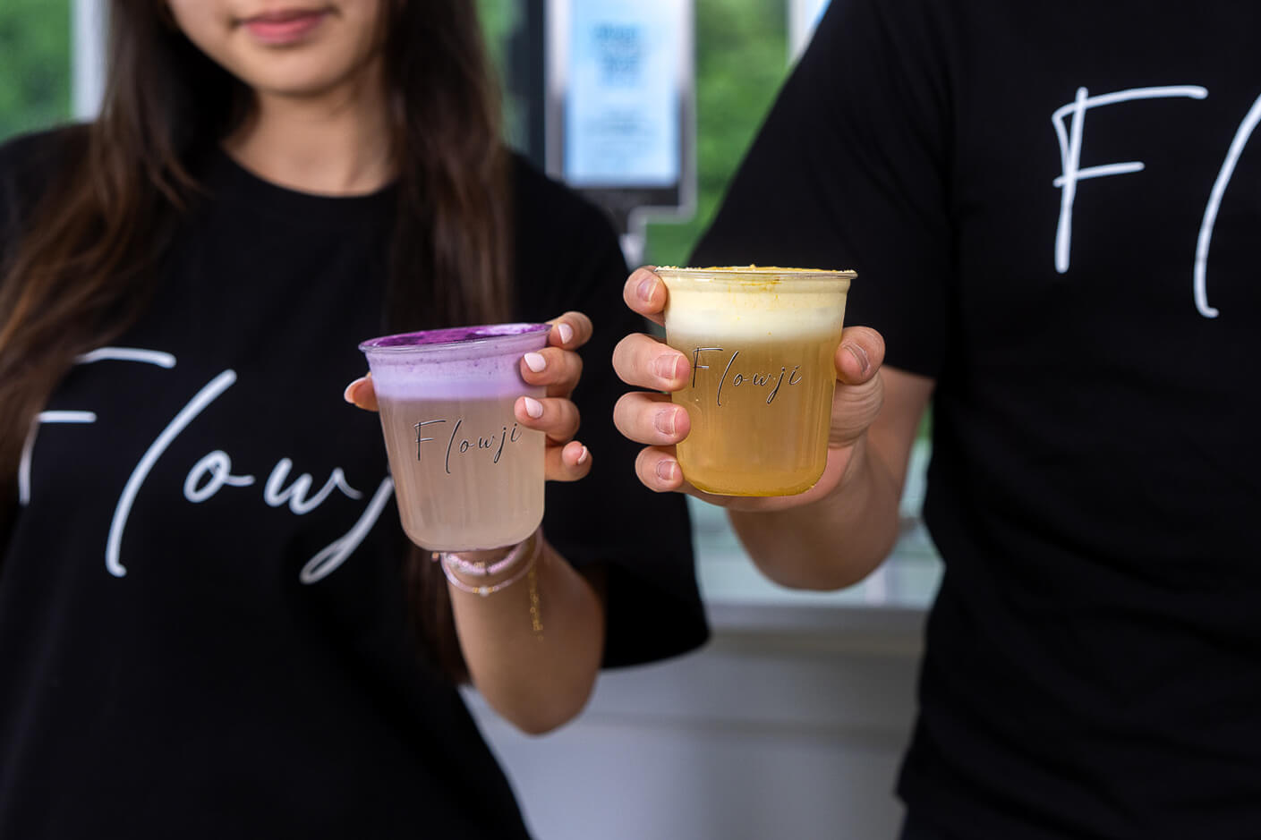 Flowji staff presenting handcrafted signature drinks in branded cups, showcasing premium mobile beverage catering for events.