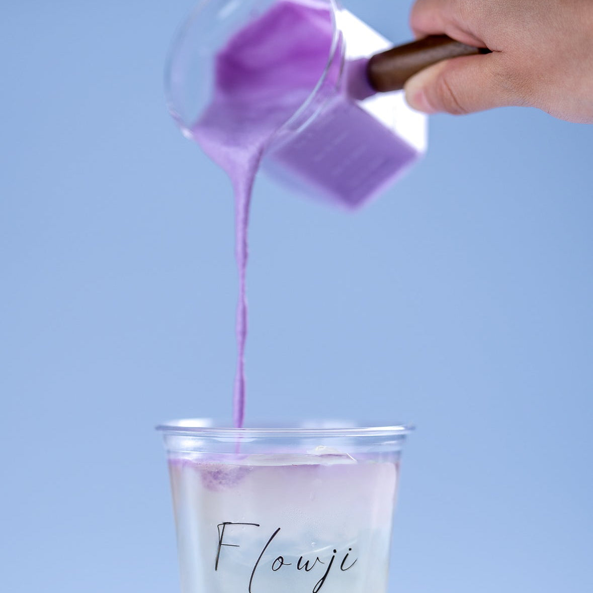 Flowji staff hand-finishing a drink by pouring handcrafted cloud foam into a freshly dispensed beverage.